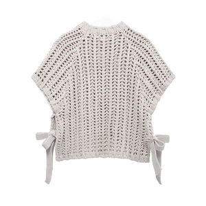 Detail of beige chunky knit vest top featuring side bow ties and textured cotton stitch