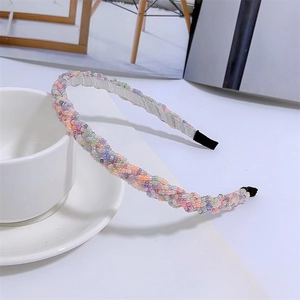 Detail of colorful beads hand-woven on a slim headband next to a white coffee cup
