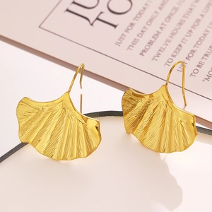 Détails macro des boucles d'oreilles feuilles de ginkgo dorées et leurs textures