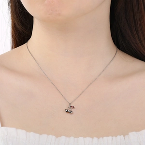 Detail of silver cherry pendant necklace with red zircon leaf on model collarbone