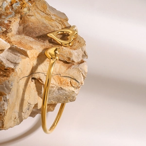 Detailed view of golden heart open bangle on a natural rock with soft lighting