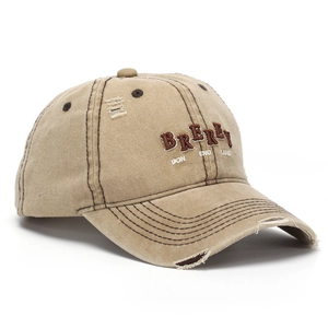 Close-up of distressed khaki baseball cap featuring vintage 3D embroidery and frayed brim