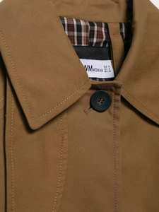 Close-up of brown trench coat featuring classic plaid lining and black button details