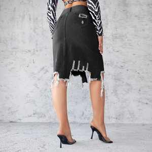 Close-up of the distressed ripped details and raw fringe hem on a black denim pencil skirt