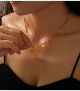 Vue détaillée d'un collier doré avec pendentif cœur évidé et perle sur un mannequin