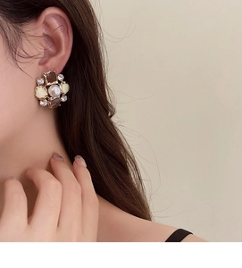 Close-up of vintage flower earrings with pearl and rhinestones on a female ear