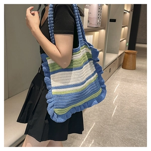 Detailed close-up of a striped crochet tote bag with ruffled edges on shoulder