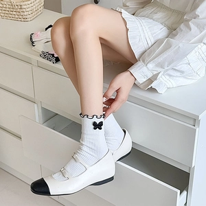 Close-up of white Lolita socks featuring black lace trim and cute bow tie details