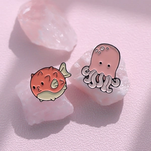 Cute cartoon pufferfish and octopus metal enamel pins on decorative pink crystals