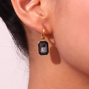 Close-up of gold hoop earrings with rectangle dark grey gemstone worn on ear