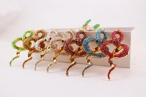 Detailed close-up of seven snake-shaped pins set with colorful rhinestones on gold base