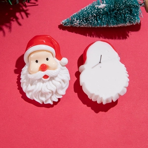 Détail des boucles d'oreilles Père Noël en résine avec tiges en métal sur fond rouge