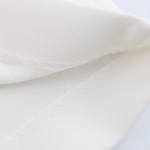 Detailed macro view of white twill fabric showing professional overlock stitching quality
