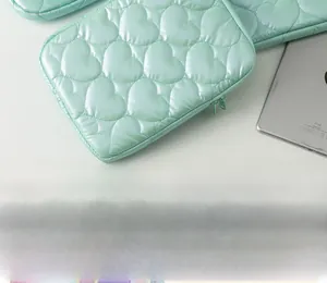 Detail of mint green padded laptop sleeve with heart-shaped quilting and smooth zipper