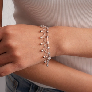 Detailed view of silver mesh tassel bracelet with delicate metallic bead charms on wrist