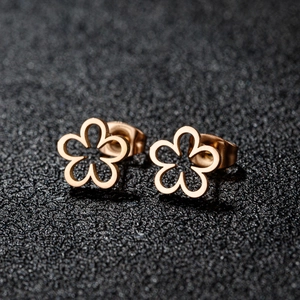 Minimalist rose gold hollow flower stud earrings displayed on a dark textured background