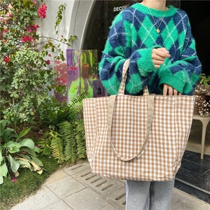 Outdoor view of a large checkered canvas tote bag with brown and white patterns