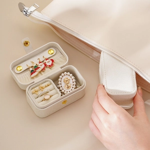 Portable mini leather jewelry box for travel shown being placed into a small handbag