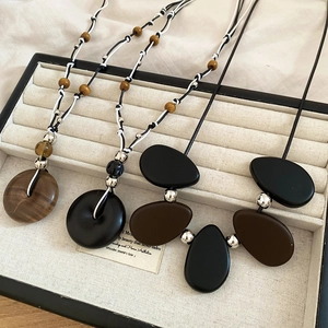 Detail of vintage resin and wood bead pendants displayed in a beige jewelry box