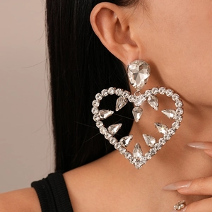 Close-up of heart drop earrings with pave diamonds and pear-shaped rhinestones