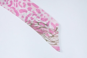 Détail du tissu à imprimé léopard rose avec plumes brunes et bords coupés en diagonale