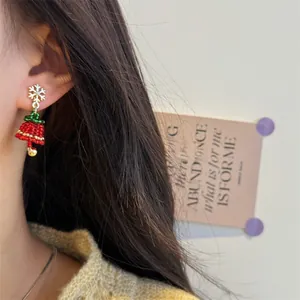 Detail of handmade Christmas tree earrings with beads and silver snowflake stud on model