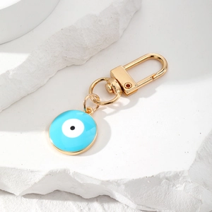 Macro shot of blue enamel evil eye charm with a polished gold lobster clasp on stone