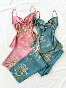 Detailed view of floral satin pajama set with cowls neck on soft white bedding