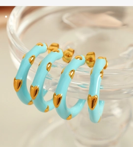 Close-up of light blue enamel heart charms on gold stainless steel C-shaped earrings