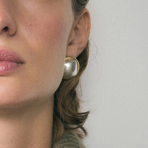 Minimalist bicolor gold and silver curved dome stud earrings worn by a model