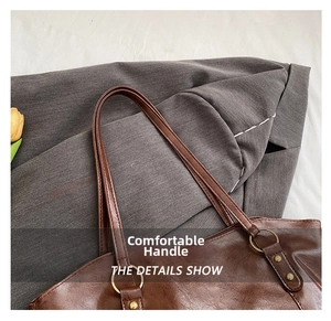 Macro detail of the brown vintage leather bag showing metal ring buckle and fine stitching