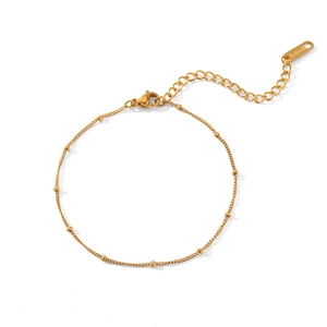 Detailed macro of golden stainless steel chain with round bead accents and lobster clasp