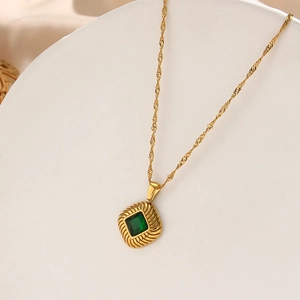 Detail of gold twisted rope chain with square green gemstone pendant and radial texture