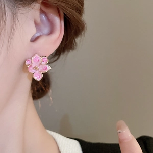 Macro view of sweet floral stud earrings with pink oil dripping and gold trim detail
