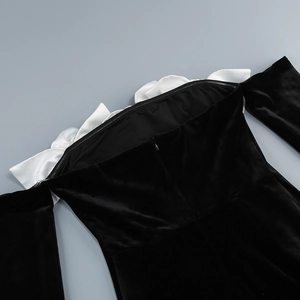 Detail of off-shoulder velvet dress showing white satin ruffle trim and hidden zipper