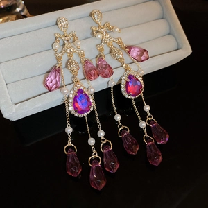 Macro detail of luxury long tassel earrings with purple crystals and pearl accents