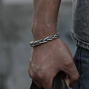 Macro view of a masculine vintage silver twisted braided open cuff bracelet on wrist