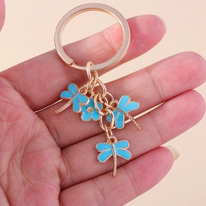 Close-up of golden dragonfly and flower keychain charms with blue enamel details