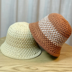 Detailed view of beige and tan hollow-out woven straw sun hats on a wooden surface