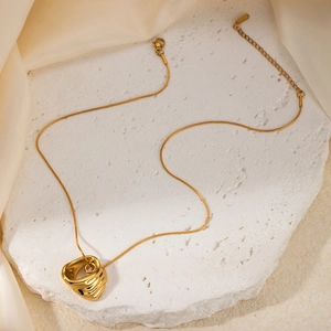 Detailed shot of golden wavy circular pendant on a sleek snake chain with adjustable clasp