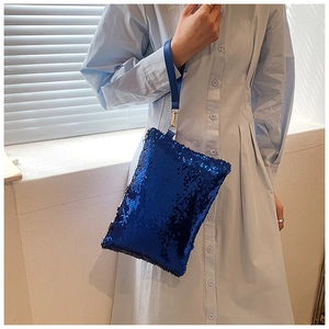Detail of royal blue sequin clutch bag showing shimmering texture and leather wrist strap