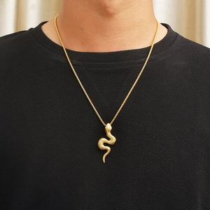 3D gold snake pendant on square box chain necklace worn by a model in black attire