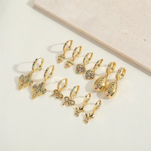 Macro detail of gold bow earrings with colorful zircon inlay on textured backdrop
