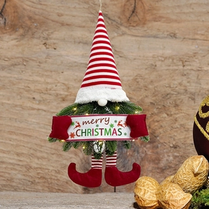 Close-up of lighted Christmas gnome wreath with Merry Christmas banner on wood wall