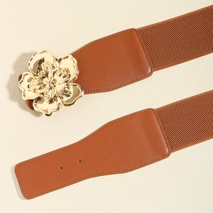 Détail d'une ceinture élastique marron avec boucle florale dorée pour manteaux