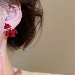 Close-up of red flocked pony earring with gold bow and pearl detail on ear