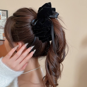Détail de l'élégante pince à cheveux en velours noir avec de longs rubans et des paillettes