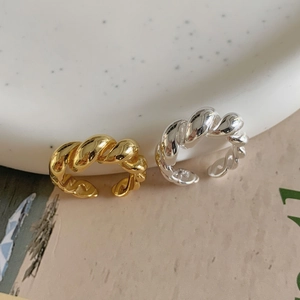 Close-up of twisted rope rings in gold and silver finish with adjustable open bands