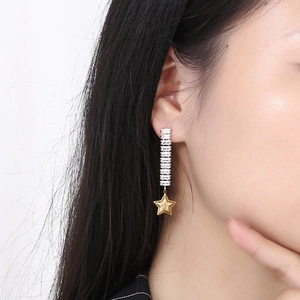 Macro shot of long gold tassel earrings with rectangular zircons and a star pendant
