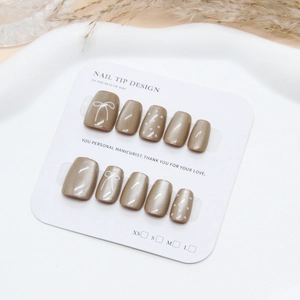 Champagne cat-eye press-on nails with white hand-painted bows and polka dots design